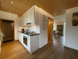 a kitchen with white cabinets and a wooden ceiling at Lovely 4 Bedroom Chalet Great for Ski Holiday in Saanenmöser