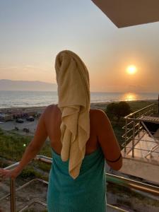 een vrouw met een handdoek op haar hoofd die naar de zonsondergang kijkt bij Relax Rental in Vlorë