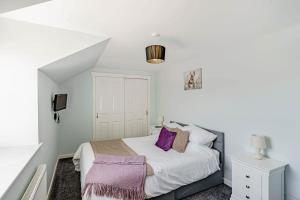 a bedroom with a bed with purple pillows at Auchenlarie Courtyard No 1 in Gatehouse of Fleet