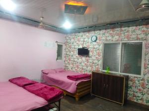 two beds in a room with pink sheets and a tv at Lakhdatar Guest house in Ujjain