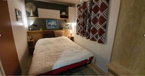 拉特斯SERENITY 565 au Lac Des Rêves-camping 4 étoiles-mobil home 3ch-6pl-clim-sdb- wc séparé-au calme, belle vue sur le lac, sans vis à vis的房间里有一张床的小卧室
