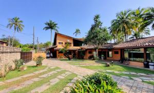 a house with a courtyard and palm trees at Monalisa Guesthouse Pé na Areia Ilhabela in Ilhabela