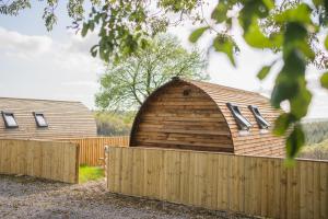 a large wooden barn behind a fence at Rivendell Farm by Wigwam Holidays in Carmarthen