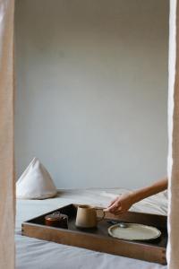 a person holding a tea pot on a tray on a bed at hOMM domek nad jeziorem in Stryszów +20 photos