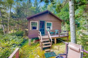 a cabin in the woods with a deck and chairs at Evergreen in Northport