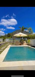 a swimming pool with an umbrella and a table and chairs at Volcano cottage bali in Kubupenlokan