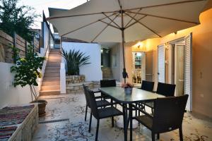 a patio with a table and chairs and an umbrella at Favola Golden Beach Villa in Daratso