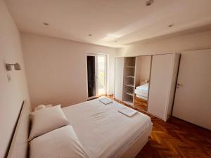 a bedroom with a white bed and a window at Apartments Anica in Primošten