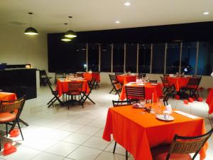 a dining room with red tables and chairs at Hotel Cristal in Turmalina