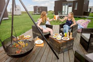three women sitting on a deck with food and drinks at Tiny House Nature 8 Innenlage - Green Tiny Village Harlesiel in Carolinensiel +22 photos