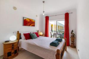 une chambre avec un grand lit avec des rideaux rouges dans l'établissement T2 Encosta São José by Gabi Miguel, à Guia