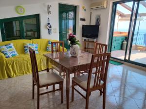 a living room with a table and chairs and a yellow couch at Casa Paradiso in Piraino