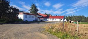 ein weißes Gebäude mit rotem Dach neben einem Feld in der Unterkunft Iceland-Aurora in Laugaras