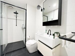 a white bathroom with a sink and a toilet at City Central 2BR Retreat on Chinatown Bourke Street in Melbourne +20 photos