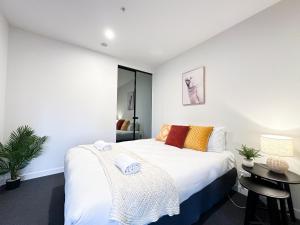 a bedroom with a large white bed and a table at City Central 2BR Retreat on Chinatown Bourke Street in Melbourne