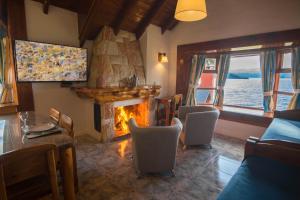 a living room with a fireplace and a table and chairs at Costa Brava Apart Hotel & Suites in San Carlos de Bariloche