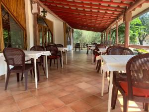 a restaurant with white tables and chairs and windows at Camping Almoetia in Calatabiano +58 photos