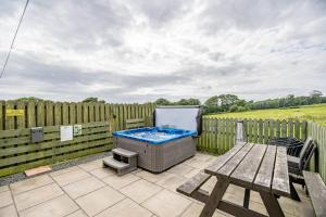 a backyard with a hot tub and a picnic table at Auchenlarie Courtyard No 4 in Gatehouse of Fleet