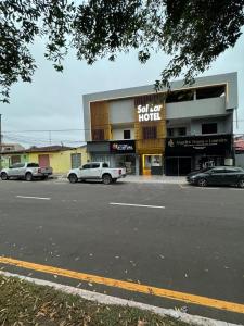 een winkel met auto's geparkeerd voor een parkeerplaats bij Sol lar hotel flats in Paragominas