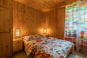 a bedroom with wooden walls and a bed with two lamps at Domki Letniskowe Kobyłocha in Kobyłocha