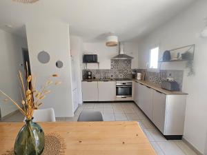 eine Küche mit weißen Schränken und einem Holztisch in der Unterkunft Charmante Maison à 500m de la plage in La Tranche-sur-Mer