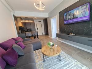 a living room with a couch and a tv on a wall at Residence Sole 5 by Wave - Apartament luxury 60mp cu terasa si vedere la mare, acces direct pe plaja OhiOhi Beach- Mamaia Nord - Restaurant, Parcare gratuita in Mamaia Sat/Năvodari