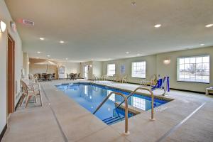 una piscina en un hotel con sillas y una mesa en Cobblestone Hotel & Suites Pulaski/Green Bay en Pulaski
