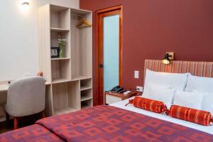 a bedroom with a bed with red walls and a desk at Mamasara Machupicchu in Machu Picchu