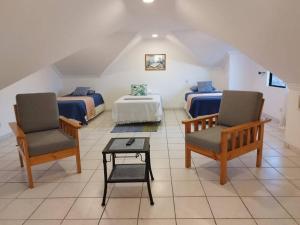 een kamer met 2 bedden, 2 stoelen en een tafel bij Hermoso Duplex Hotel BUGANVILLAS in Santa Cruz de la Sierra
