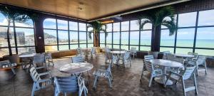 a restaurant with tables and chairs and a view of the ocean at Flat Pasárgada 712 - apt com vista para a Praia da Costa, academia moderna, piscinas panorâmicas, minimercado e lavanderia in Vila Velha