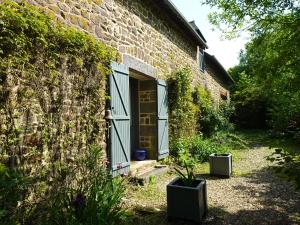a brick house with a door and plants in front of it at Le Domaine in Les Iffs