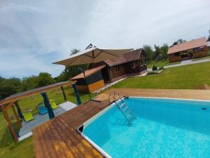 a swimming pool with an umbrella and a house at Kuća za odmor Jopi i Mare in Topusko