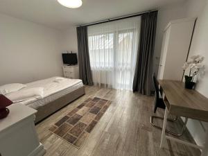 a bedroom with a bed and a desk and a window at The View Apartment 3 Bușteni in Buşteni