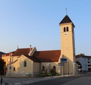 a church with a clock tower on a street at XXXL 10 personnes in Bellignat