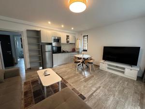 ein Wohnzimmer mit einem Sofa, einem TV und einem Tisch in der Unterkunft The View Apartment 3 Bușteni in Buşteni