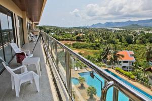 a balcony with two chairs and a swimming pool at Serenity Shores - 2 King Bed - Beachfront Penthouse in Plai Laem