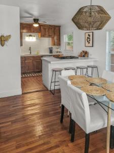 a kitchen with a table and some white chairs at Simply Get-A-Waco- HOT TUB, Sleeps 10, 5-min Walk to Silos & Downtown Waco in Waco