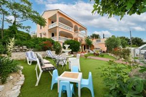 una casa con cortile attrezzato con sedie e tavoli di Villa Schubert a Novalja (Novaglia)