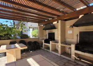 a patio with an outdoor kitchen with a wooden pergola at Depto Centro Viña in Viña del Mar