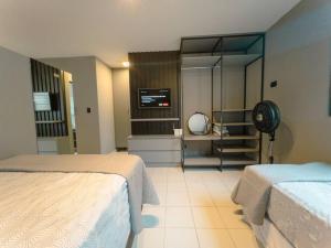 a hotel room with two beds and a tv at Apartamento Moderno Zona 7 LP13 in Maringá
