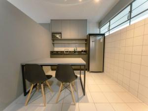 a kitchen with a table and two chairs and a refrigerator at Apartamento Moderno Zona 7 LP13 in Maringá