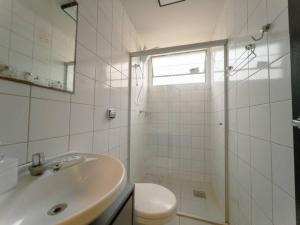 a white bathroom with a sink and a toilet at Apartamento Moderno Zona 7 LP13 in Maringá