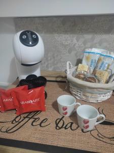 a coffee maker next to two cups and a basket of cookies at Kamurria House in Catania
