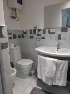 a white bathroom with a toilet and a sink at Kamurria House in Catania