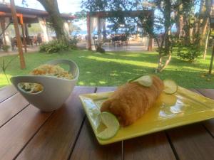 a plate of food with a roll and a bowl of food at Hotel Porto Di Mare in Ubatuba