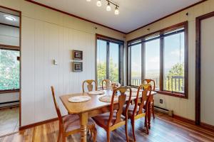 Un comedor con mesa y sillas y ventanas. en Skyleaf 703, en Sugar Mountain