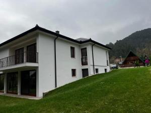 a white house on top of a green hill at Villa Bella Una-Apartman in Ostrožac