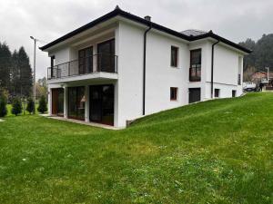 a white house on top of a green hill at Villa Bella Una-Apartman in Ostrožac