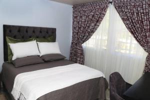 une chambre avec un lit et une fenêtre avec des rideaux dans l'établissement Yellow Wood Cottage, à Kambanji