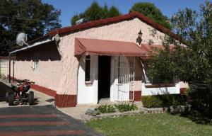 une petite maison avec une moto garée devant elle dans l'établissement Yellow Wood Cottage, à Kambanji